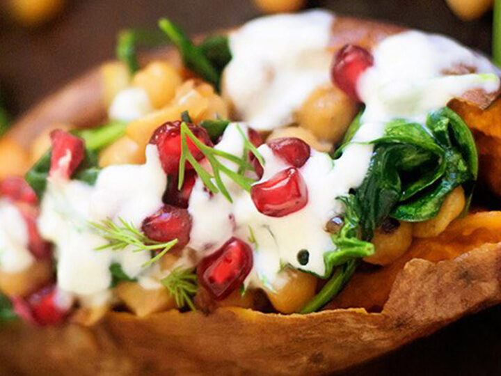 chickpea and spinach stuffed swet potato loaded with greek yogurt sauce and fresh pomegranate