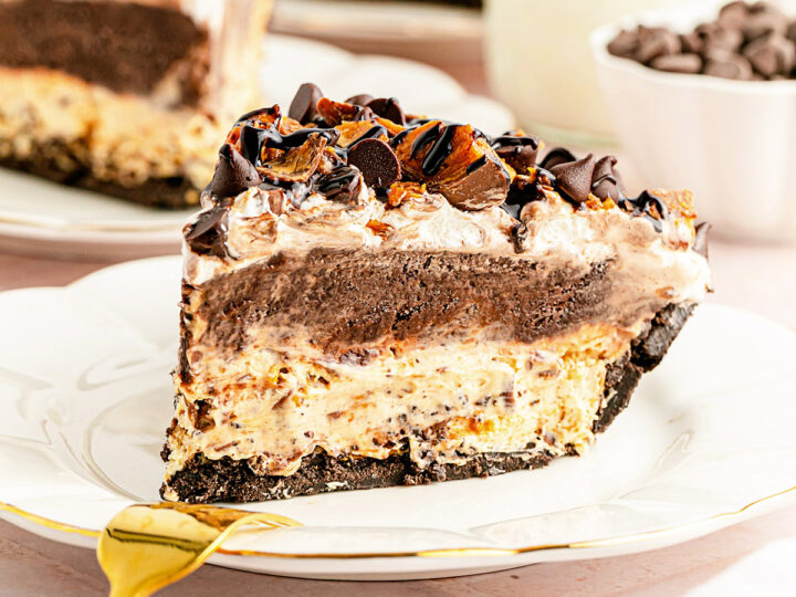 A slice of decadent, creamy pie on a white plate, with a thick chocolate filling and crumbled Butterfinger candy bar pieces on top. The crust appears to be made of crushed chocolate cookies, adding to the richness of the dessert.