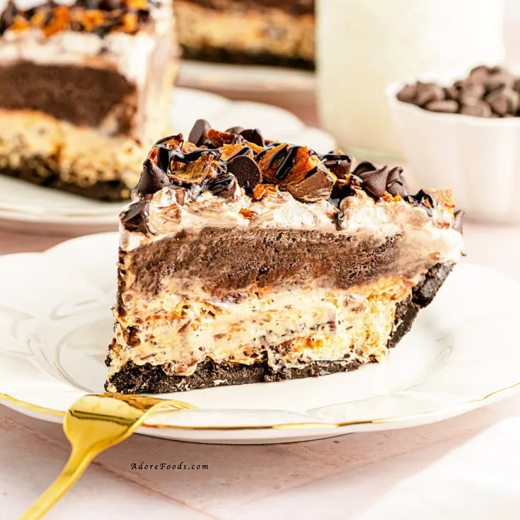 A slice of decadent, creamy pie on a white plate, with a thick chocolate filling and crumbled Butterfinger candy bar pieces on top. The crust appears to be made of crushed chocolate cookies, adding to the richness of the dessert.