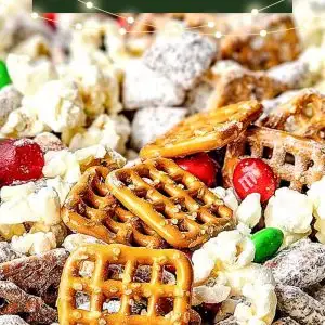 Festive homemade Chex Mix served in a bright red ceramic bowl for Christmas. The snack mix features golden brown toasted cereal squares, pretzel twists, round cheese crackers, and roasted nuts, all lightly coated with seasoning for a shiny, crunchy texture. The bold red color of the bowl adds a holiday touch, complementing the mix&rsquo;s warm tones of gold and brown, while the background hints at a cozy Christmas setting perfect for parties, gifting, or family snacking.